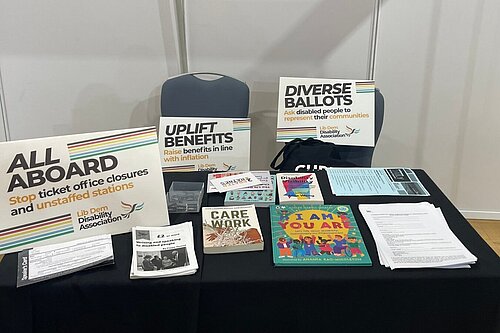 An LDDA stall table packed with placards and leaflets