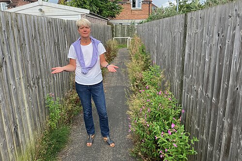 Councillor Paula Widdowson standing in the overgrown Carrfield snicket