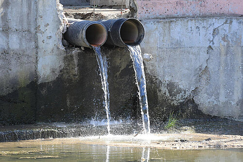 Dirty water pouring from pipe into water course