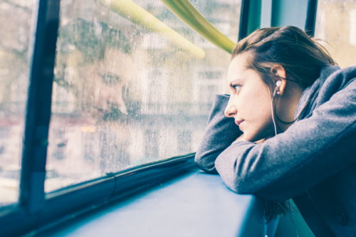 A woman looks out of a window on the top deck of a London Bus.