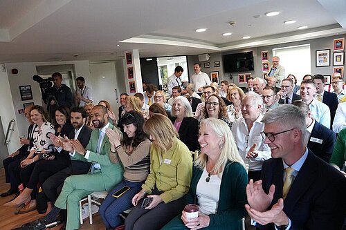 The new Liberal Democrat MPs including Susan Murray all sitting in rows with happy faces and clapping.